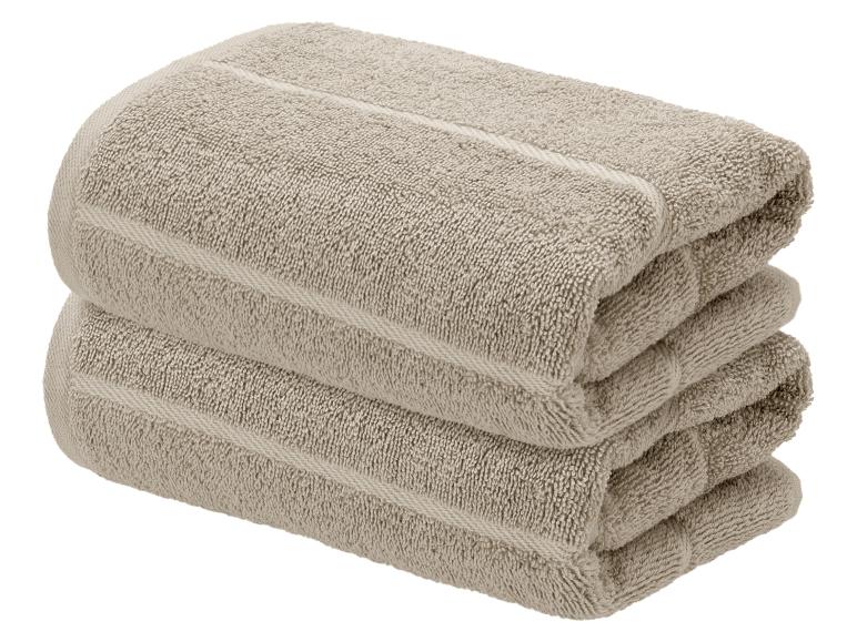 Zwei gestapelte beige Handtücher mit Streifenmuster.