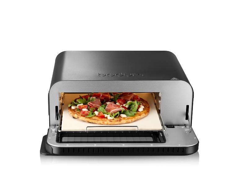 Ein Bodum Pizzaofen mit einer Pizza mit Schinken, Rucola und Tomaten