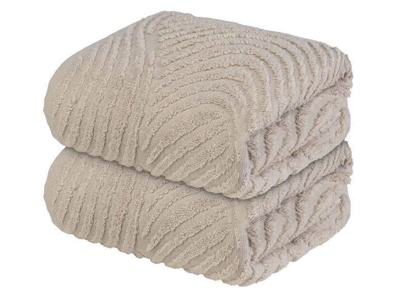 Zwei beige Handtücher mit einem gerippten Muster.