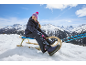 Mädchen in Schneeanzug und Mütze, auf einem Schlitten in den verschneiten Bergen.