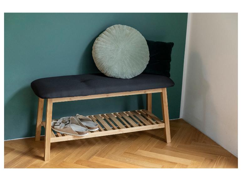 Eine Bambus-Schuhbank mit gepolsterter Sitzfläche, ein Paar Sandalen und dekorative Kissen.