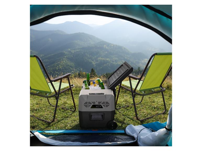 Tragbare Kühlbox mit Getränken und Campingstühlen vor einer Berglandschaft.
