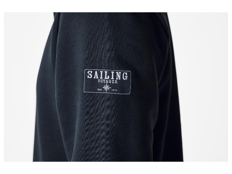Schwarzer Sweatshirt-Ärmel mit „SAILING VOYAGER EST 1976“-Emblem und Windrose.