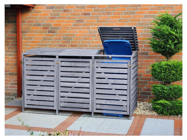 Ein graues, hölzernes Containerhaus mit blauen Mülleimern.
