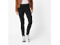 Frau in brauner Jacke, weißem T-Shirt, schwarzen Jeans und weißen Sneakern.