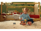 Mädchen spielt mit Holzspielzeug-Autotransporter in weihnachtlich dekoriertem Kinderzimmer.