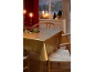 Festlicher Esstisch mit goldener Tischdecke, roten Kerzen und Weihnachtsdekorationen.