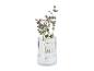 Gerillte Glasvase mit Eukalyptus und lila Blumen.