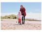 Mutter und Kind in wasserdichten Jacken und Hosen am Strand.