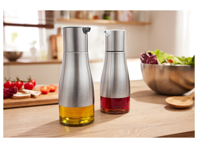 Zwei Ölflaschen aus Edelstahl mit Öl und Essig auf einem Holztisch