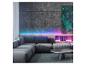 Modernes Wohnzimmer mit grauem Ecksofa, rundem Couchtisch und farbiger LED-Beleuchtung.