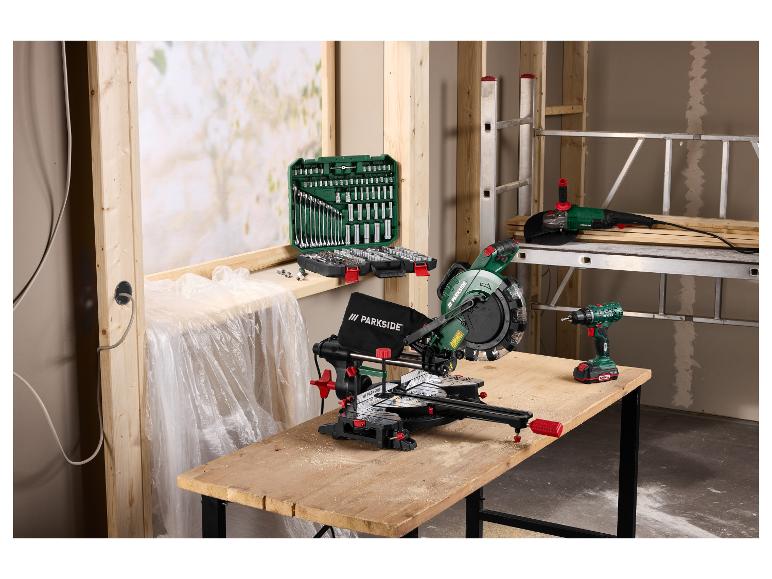 Kappsäge, Winkelschleifer und Bohrmaschine auf einer Werkbank mit Steckschlüsselsatz in einer Werkstatt.