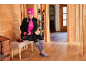 Frau bereitet sich auf das Skifahren vor, trägt eine pinke Mütze, schwarze Jacke, pinkes Shirt, schwarze Hose und graue Socken.