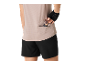 Frau in Sportshirt und Shorts, die einen Energieriegel aus der Gesäßtasche nimmt.