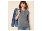 Frau in grauem Langarm-Poloshirt und blauer Jeans, eine Jeansjacke haltend.