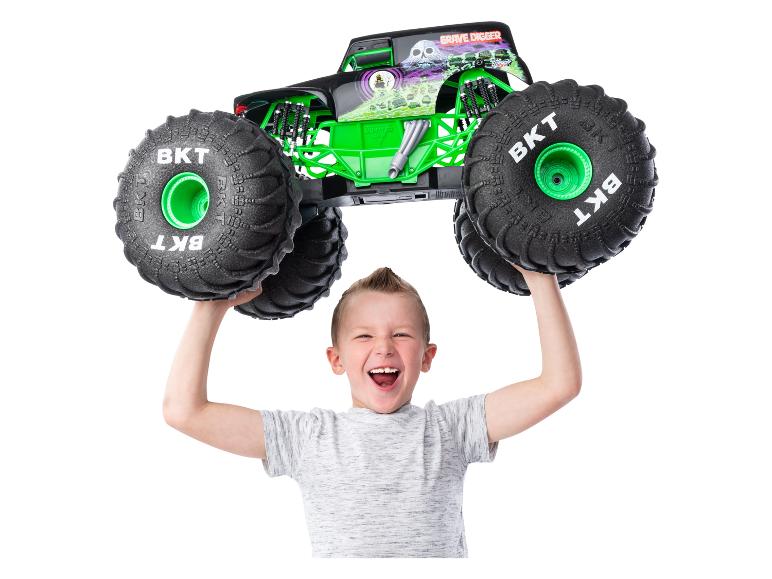 Ein Junge hält ein Grave Digger Monster Jam Monstertruck-Spielzeug über seinem Kopf.