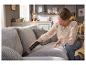Frau saugt Krümel vom Sofa mit einem Silvercrest Handstaubsauger.
