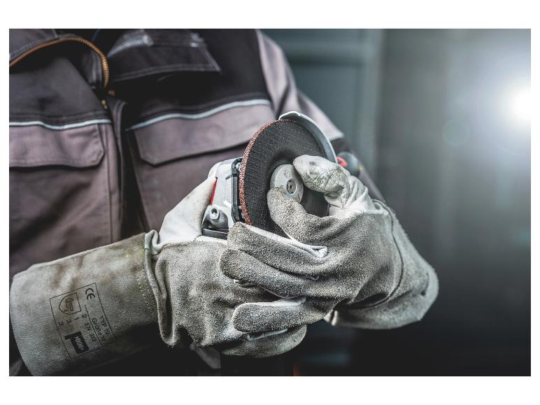 Hände in Schutzhandschuhen halten einen Winkelschleifer mit Schleifscheibe.