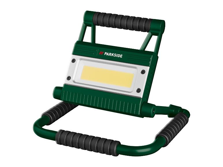 Eine grüne und schwarze tragbare LED-Arbeitsleuchte mit einem hellgelben Lichtpanel.