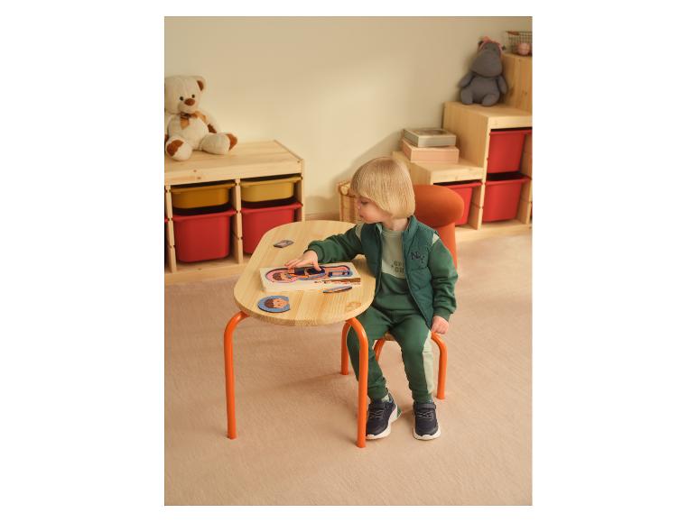 Kleinkind in LUPILU® Wende-Steppweste spielt an einem Tisch.