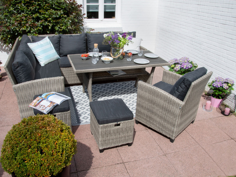 Eine Wicker-Lounge-Garnitur mit Tisch, Sofa, zwei Sesseln und einem Hocker auf einer Terrasse.