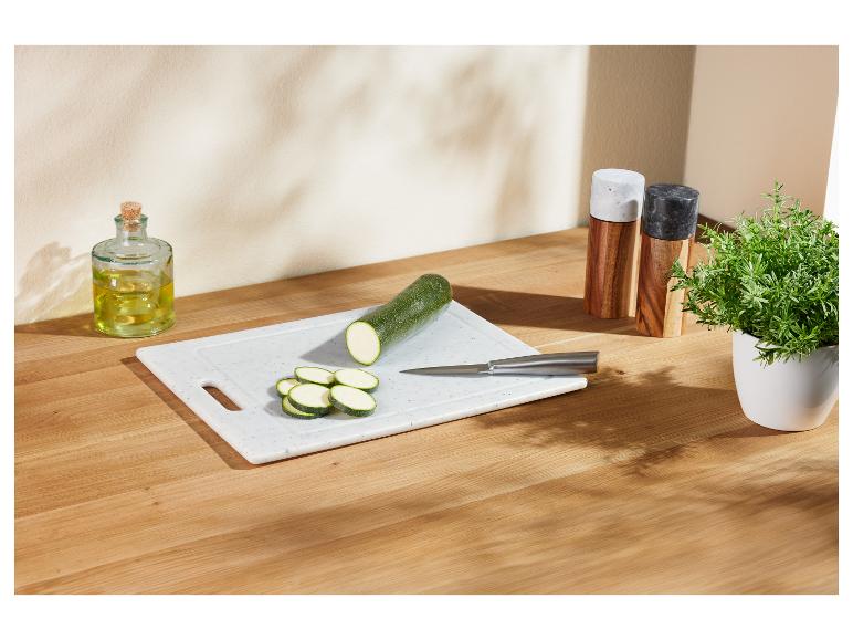 Geschnittene Zucchini auf einem Schneidebrett, mit Olivenöl und Kräutern.