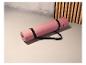 Eine rosa Yogamatte von Crivit mit einem schwarzen Trageriemen.