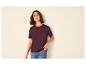 Frau in bordeauxfarbenem T-Shirt und Jeans, mit der Hand in der Tasche.