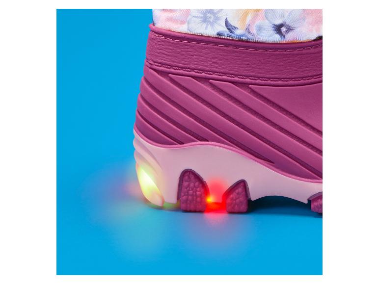 Ein pinker Stiefel mit blinkenden Lichtern an der Sohle, auf blauem Hintergrund.