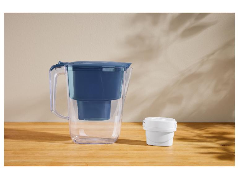Wasserfilterkanne mit blauem Deckel und einem weißen Ersatzfilter auf einer Holzoberfläche.
