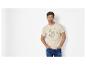 Mann in hellbeigem T-Shirt mit Schildkrötengrafik und Text, blaue Jeans