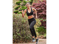 Eine Frau in schwarzem Sport-BH und Leggings rennt durch den Wald.