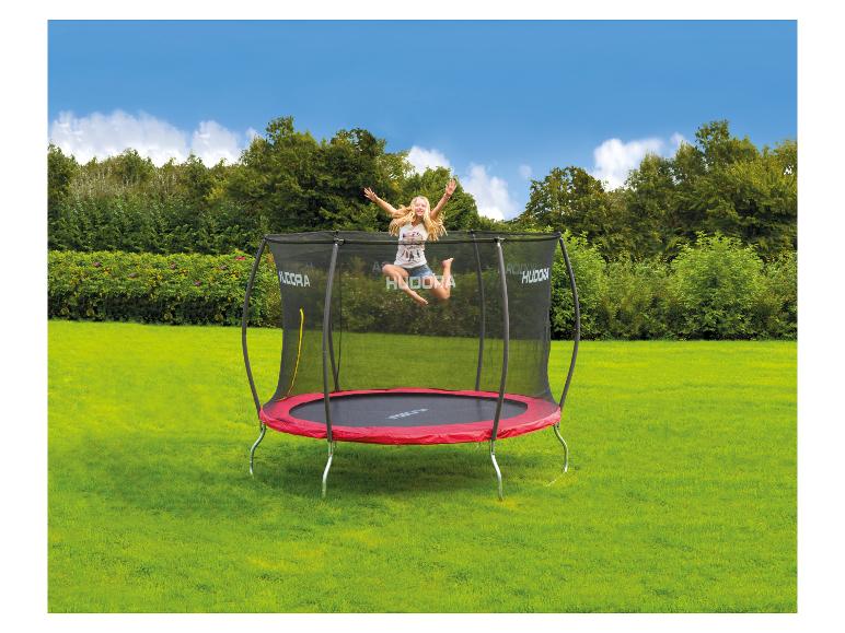 Blondes Mädchen springt auf einem roten und schwarzen Hudora Trampolin in einem grünen Garten.