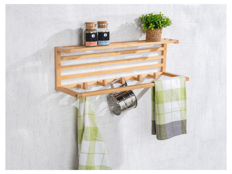 Ein Wandregal aus Holz mit Handtüchern, einem Sieb und Gewürzgläsern.