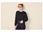 Frau in schwarzem Pullover, gestreiftem Hemd, dunklen Jeans und gelber Sonnenbrille.