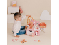 Junge spielt mit einer rosa Puppenpflegestation mit Babypuppe und Zubehör.