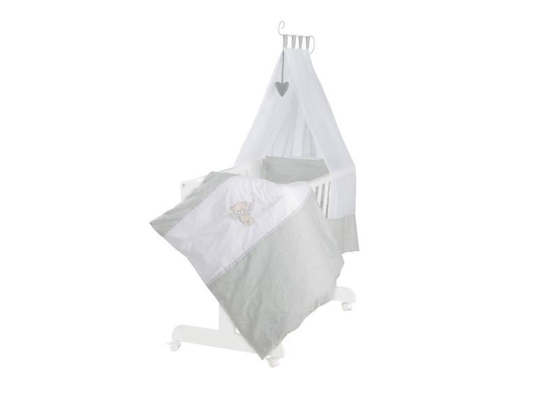 Weißes Babybett mit Himmel und grau-weißer Bettwäsche mit Teddybär