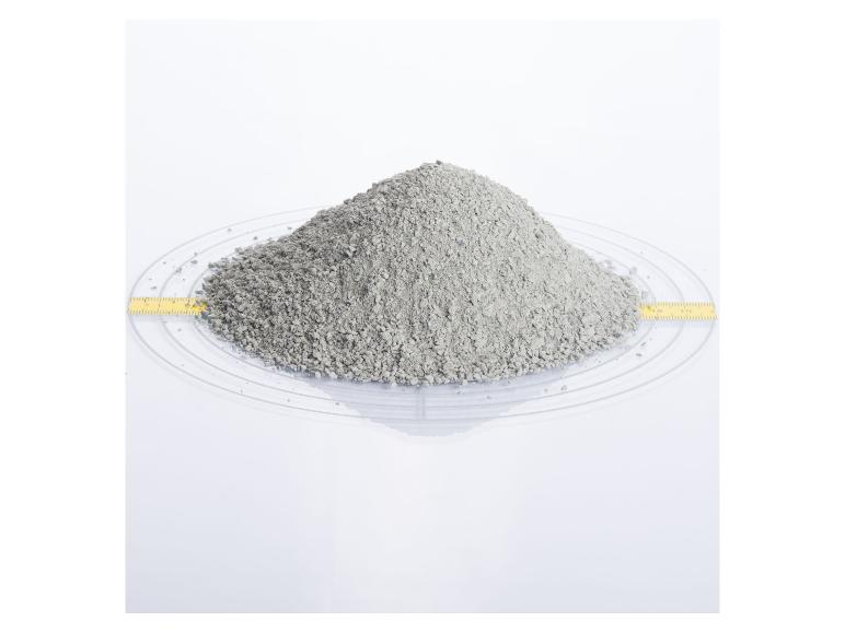 Ein Haufen graues Katzenstreu auf einer transparenten Unterlage mit Maßband.