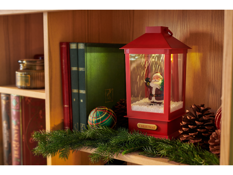 Weihnachtslaterne mit Weihnachtsmannfigur, Büchern und Tannengirlande auf einem Holzregal.