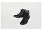 Zwei schwarze Stiefel, einer auf einem weißen Podest, der andere auf dem Boden.