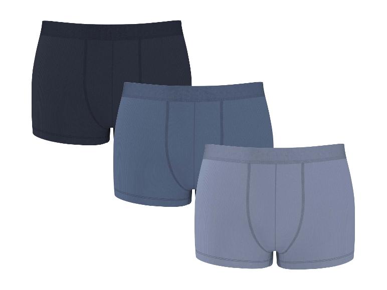 Drei gerippte Baumwoll-Boxershorts in Blau- und Grautönen.