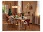 Elegant gedeckter Weihnachtstisch mit Holzstühlen und festlicher Dekoration.