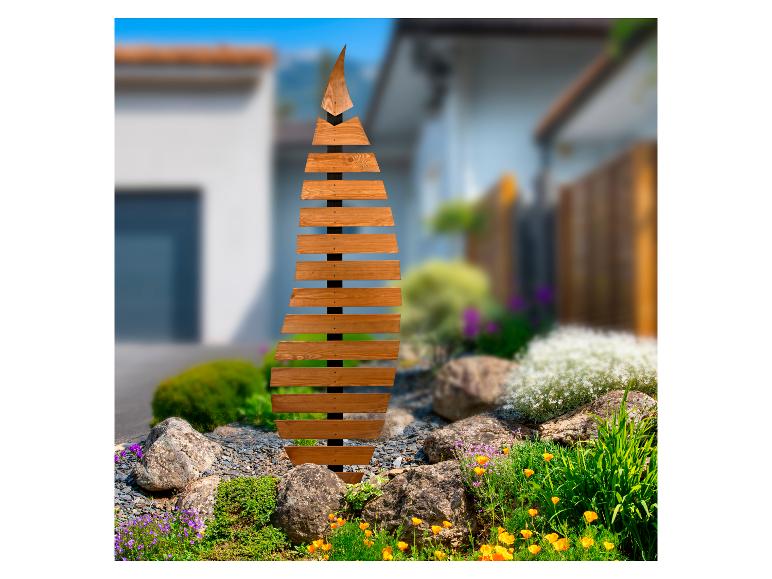 Hölzerne Weihnachtsdekoration in Baumform in einem Garten mit Blumen und Steinen.