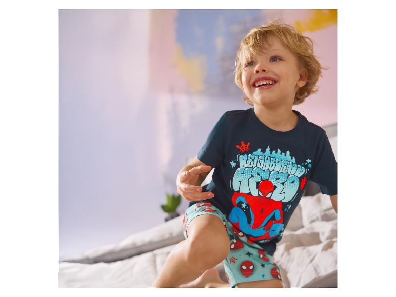 Kind im Bett, das einen LUPILU® Kinderpyjama im Spider-Man-Design trägt.