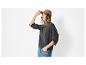 Frau in grauem Pullover, Jeans und rosa Kappe, mit der Hand am Schirm.