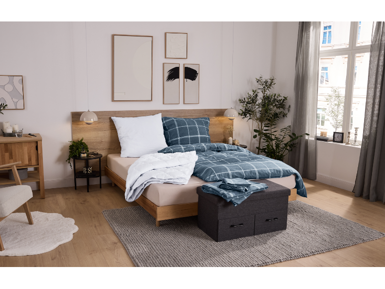 Schlafzimmer mit Holzbett, blauer karierter Bettwäsche und grauem Teppich.