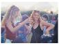 Festivalbesucher tanzen, Boho-Outfits, sommerliche Stimmung.