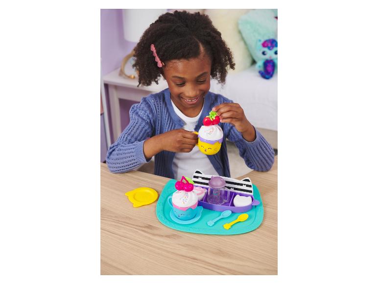 Ein Mädchen spielt mit einem Katzen-Tee-Set.