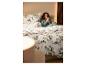Frau im Bett mit weicher LIVARNO® Feinbiber-Bettwäsche mit Winterwald-Motiv.