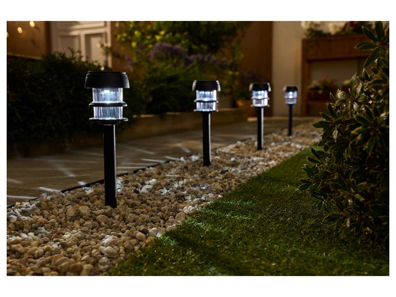 Gartenweg beleuchtet von Solarlampen, mit Kies und Gras.